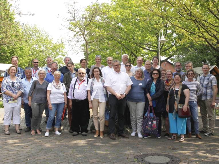 30 Personen schauen zum Bildbetrachter, dahinter sind Bäume.